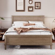 a bed with white sheets and pillows in a bedroom next to pictures on the wall