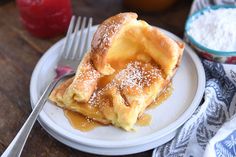 a white plate topped with powdered sugar covered pastry next to a jar of jelly