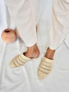 We fell in love with these lightweight shoes and now we want to share this love with you! The slippers are handcrafted in Morocco following old traditions. It takes one day to finish one pair of shoes: That's slow fashion! The upper material is made from palm leaves (raffia), the outer sole is in structured anti-slippery rubber and the inner sole is in dark brown vegan leather with logo embossing. The design is unique and furthermore super comfortable. We don't wanna take them off anymore. ~ Handmade in Morocco. ~ If you are between two sizes, we recommend you choose the larger one, as they run a little smaller. EU 36: US 5 / UK 3 EU 37: US 6 / UK 4 EU 38: US 7 / UK 5 EU 39: US 8 / UK 6 EU 40: US 9 / UK 7 EU 41: US 10 / UK 8 EU 42: US 11 / UK 9 Beige Slip-on Mules With Woven Sole, Cream Slip-on Clogs For Summer, Cream Slip-on Slippers, Cream Closed Toe Slip-ons, White Mules With Rubber Sole For Beach, Beige Slip-on Slippers With Leather Sole, Beige Slip-on Slippers With Closed Toe, Beige Closed Toe Slip-on Slippers, Beige Slip-on Closed Toe Slippers