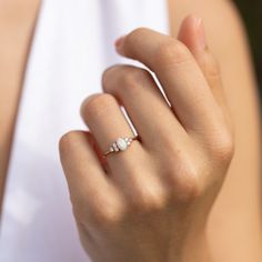 a woman's hand wearing a gold ring with three stones on it and a diamond band