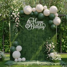 an outdoor birthday party with balloons and greenery on the grass, surrounded by flowers