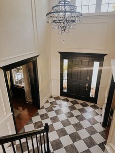 an entry way with black and white checkered flooring, chandelier and door