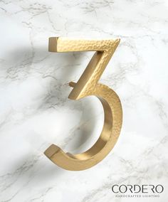 the number five is made out of gold metal and sits on a marble countertop