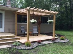 a wooden deck with chairs and flowers in the middle of it next to a house