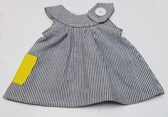 a striped dress with a yellow patch on the chest and collar, sitting on a white surface