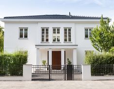 a white house with green shutters and black gate