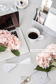 a laptop computer sitting on top of a desk next to a bouquet of pink flowers