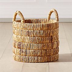 a large woven basket sitting on top of a hard wood floor next to a white wall