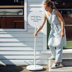 a woman standing next to a white sign