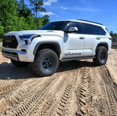 a white truck parked on top of a dirt road