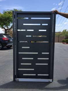 a man is holding up a large black door in the middle of a parking lot