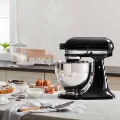 an image of a kitchen scene with focus on the mixer and ingredients for making cake