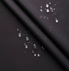 drops of water are on the surface of a black fabric, which is very dark