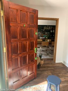 an open wooden door leading to a dining room and living room with blue stools