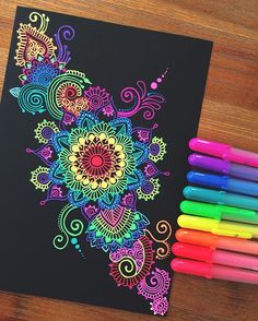 some markers are laying on top of a coloring book with an intricate design and colors