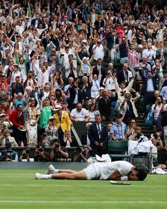 a tennis player laying on the ground in front of a crowd