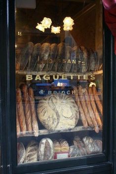 breads and baguettes are displayed in a bakery window