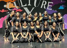 a group of young women standing on top of a stage next to each other in front of a sign