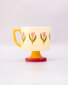 side view of top view of cream 10 oz ceramic mug with yellow handle, pink pedestal base and pink tulip print Pretty Ceramic Mugs, Tulip Mug, Tech Books, Color Me Mine, Local Thrift Stores, Desk Planners, Choppy Bob, Book Clothes, Host Gifts