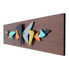 three fish are mounted to the side of a wooden wall hanging on a wood panel