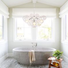 a bathroom with a claw foot bathtub and wooden stools in front of two windows