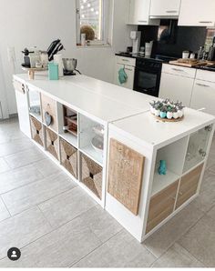 a kitchen with white cabinets and wooden drawers on the counter top is decorated with baskets