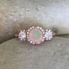 A lovely 3 Stone featuring a radiant, genuine natural round-shaped Opal prong set in Rose Gold Plated over Sterling Silver or Sterling Silver accented with cubic zirconia shank. This ring makes a lovely engagement/promise/statement ring. You have the option to pair it with a matching band Elegant Three Stone Opal Ring, Elegant Three-stone Opal Ring, Elegant Three Stone Round Opal Ring, Three Stone Round Cut Jewelry For Proposal, Elegant Three Stone Opal Promise Ring, Round Three Stone Jewelry For Proposal, Three Stone Round Jewelry For Proposal, Elegant Three Stone Opal Wedding Ring, Fine Jewelry Three Stone Opal Wedding Ring