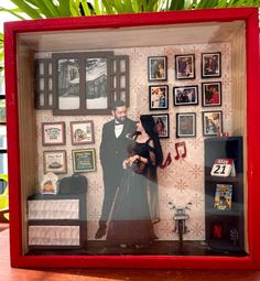 a red frame holds a photo of a man and woman in formal wear, surrounded by many framed photos