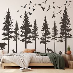 a bed sitting under a tree filled wall with birds flying over it