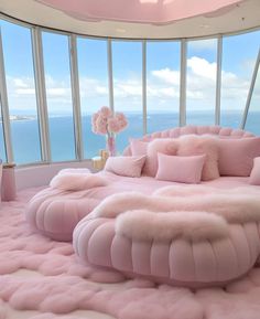 a bedroom with pink furniture and large windows overlooking the ocean