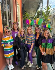 a group of women standing next to each other in front of a building wearing mardi gras costumes