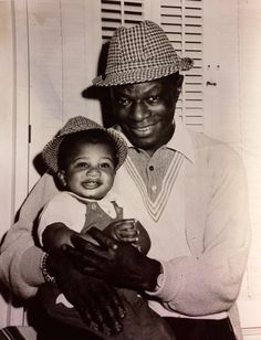 an old black and white photo of a man holding a baby