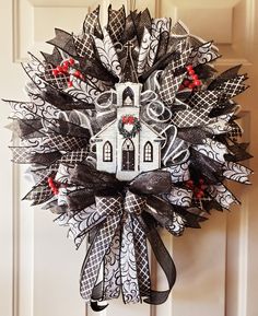 a black and white wreath with a church on it hanging from the front door,