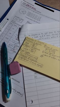 a pile of papers and pens on top of each other next to a calculator