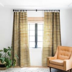 a chair sitting in front of a window next to a potted plant on top of a rug