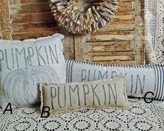 three pillows with pumpkins on them sitting next to an old door and lace doily