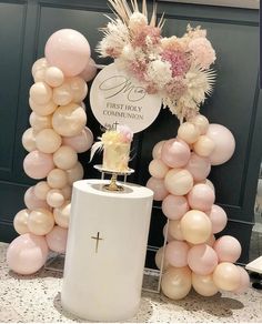 a table topped with balloons and a cake on top of a pedestal next to a cross