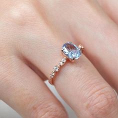 a woman's hand with a ring on it and an oval blue stone in the middle