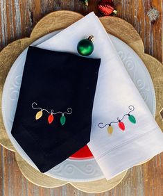 two black and white napkins sitting on top of a plate next to christmas ornaments