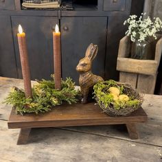 a wooden table topped with candles and a bunny figurine sitting on top of it