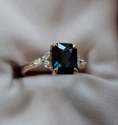 a fancy ring with a blue stone surrounded by three white diamonds on a beige cloth