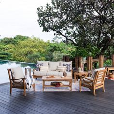 an outdoor deck with chairs, tables and couches on it next to a body of water