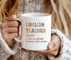 a woman is holding a coffee mug with english teacher written on the front and side