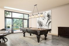 a pool table is in the middle of a room with large windows and sliding glass doors