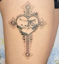 a cross tattoo with a cat on it's side and a heart in the middle