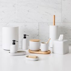 the bathroom accessories are all white and have wood accents on them, including soap dispenser