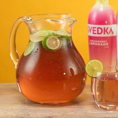 a pitcher of water with limes and a glass next to it