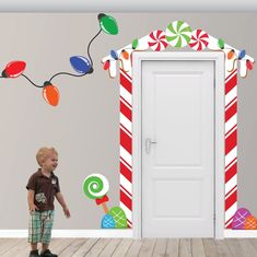 a young boy standing in front of a door with candy canes and christmas lights