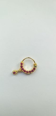 a gold ring with pink stones on the side and a small bead around it