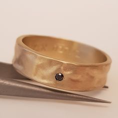 Unique 18k Textured Gold Wedding Band for Men. This Hammered gold band has a natural and elegant look. This 6mm wide ring sits with beautiful proportion and harmony on the hand. This wedding band has an organic texture shape and style. A truly classic and original piece. This Hammered gold ring is set with one small black diamond in the band. Adding a touch of color and personality to this ring. This ring can be made with any different color diamond or gemstone. Please contact me for a custom re Wedding Ring With Single Cut Diamonds And Thick Band, Yellow Gold Band With Single Diamond For Anniversary, Yellow Gold Anniversary Band With Single Diamond, Anniversary Yellow Gold Band With Single Diamond, Thick Band Jewelry With Single Cut Diamonds For Wedding, Wedding Hammered Diamond Jewelry, Hammered Yellow Gold Round Bands, Hammered Yellow Gold Bands, Wide Band Wedding Jewelry With Single Diamond